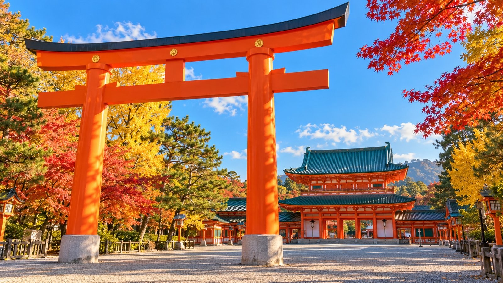 朱紅色大鳥居和綠瓦神社建築，藍天下兩旁是紅黃色秋葉