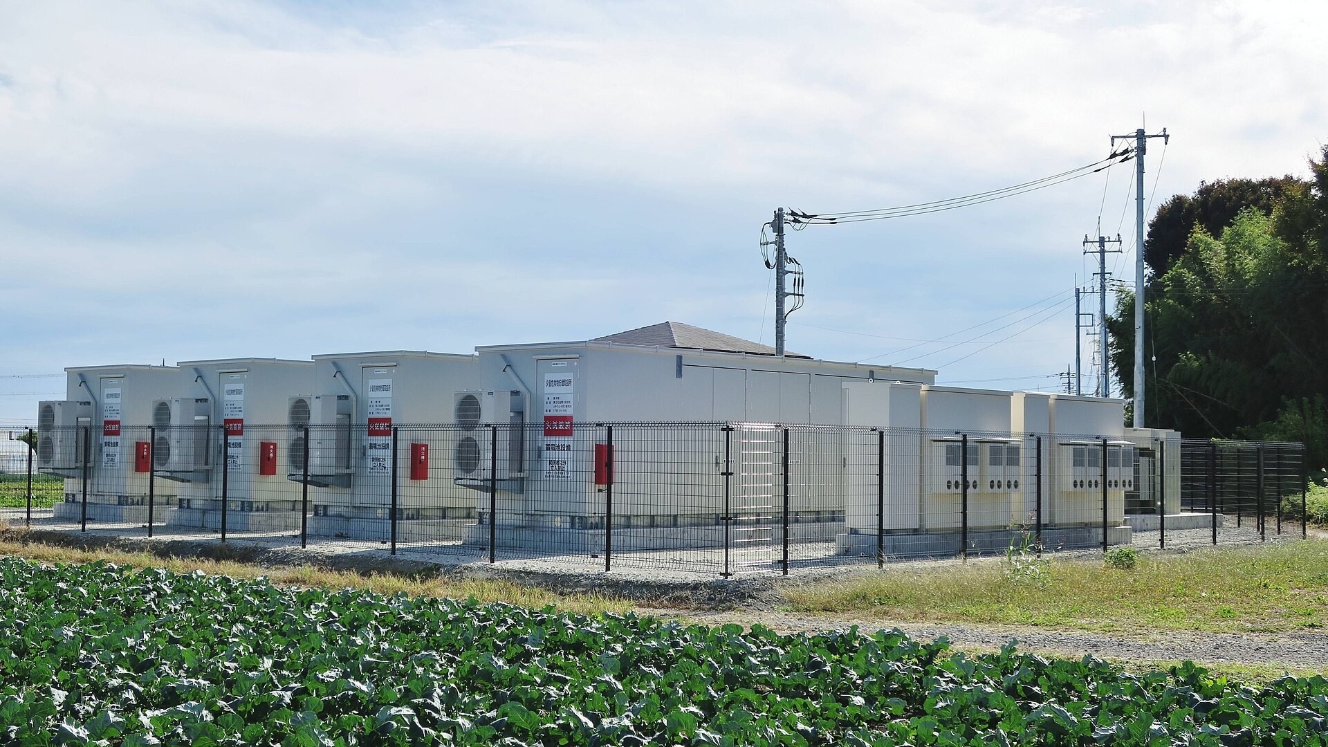Grid-connected lithium-ion battery energy storage station (Nirazuka Battery Storage Power Station in Isesaki, Gunma Prefecture, Japan, photographed in 2025), showing containerized battery units and power conversion equipment
