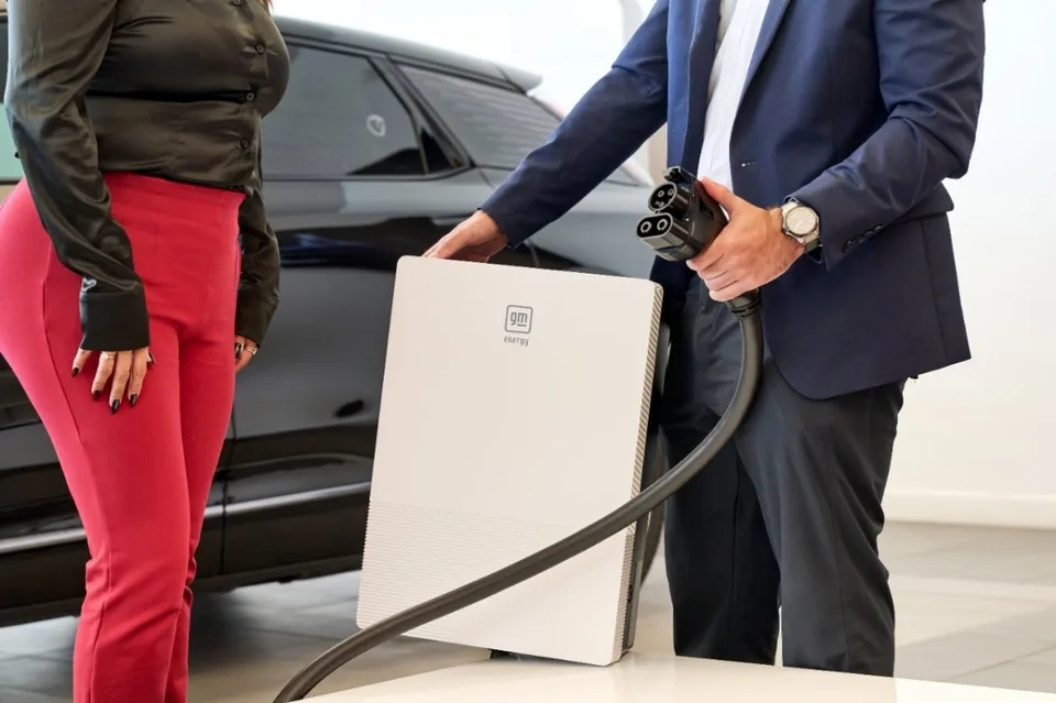 電気自動車の前に置かれた白い壁掛け型GM Energy PowerShift充電器と充電コネクター
